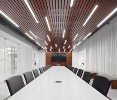 an empty conference room with white walls and wooden ceilinging, along with black leather chairs