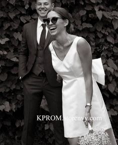 a man in a suit and tie standing next to a woman in a white dress