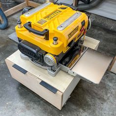 a yellow machine sitting on top of a wooden box