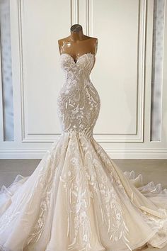 a wedding dress is displayed on a mannequin in front of a white wall