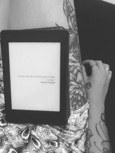 a woman with tattoos is holding an electronic device in her lap and writing on the screen