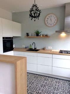 a kitchen with white cabinets and a clock on the wall