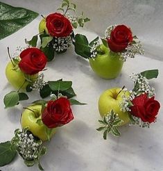 there are many roses in the vases on the table with apples and baby's breath