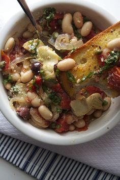 a white bowl filled with beans and vegetables on top of a blue and white napkin