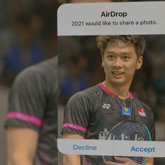 a man holding a tennis racquet in front of a sign that says airdrop