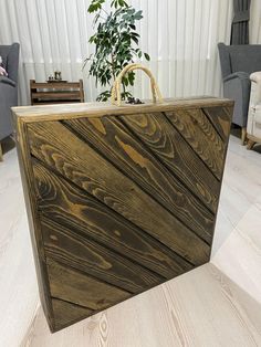 a wooden box sitting on top of a hard wood floor next to a chair and potted plant