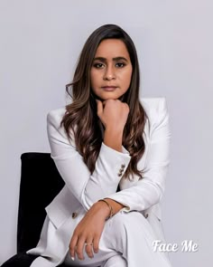 a woman sitting in a chair with her hand on her chin and looking at the camera