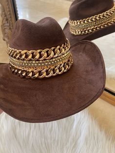 Our love of hats just got became a full-on obsession: meet the Beth Dutton Chain Banded cowboy hat! The most chic, high-end hat we could've ever dreamed up. A hat this good needs to be worn as much as possible and with every single outfit! Hand made by artisans, incredible quality, pure suede, hand placed chain around the crown, too many details to list! The best part? It's super structured with an elastic band on the inside that will fit EVERYONE. Btw never taking this hat off. These hats are a Gold Fedora Hat For Rodeo, Gold Fedora Western Hat, Gold Western Fedora Hat, Gold Short Brim Hats For Country Events, Western Gold Fedora With Short Brim, Gold Western Hat Band For Kentucky Derby, Western Gold Hat Bands For Kentucky Derby, Western Style Gold Fedora With Short Brim, Gold Western Hat Band For Western-themed Events