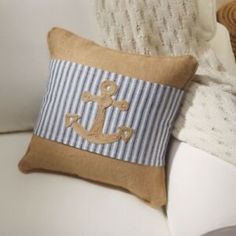 a pillow with an anchor on it is sitting on a white couch next to a wicker basket