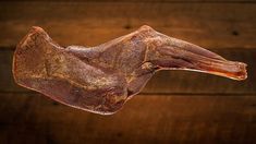 a piece of raw meat hanging from a hook on a wooden table with wood planks in the background