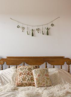 a bed with two pillows on top of it next to a wooden headboard and wall hanging