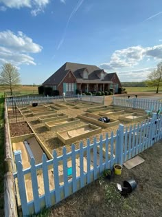 a large yard with several raised beds in the middle and a white picket fence surrounding it