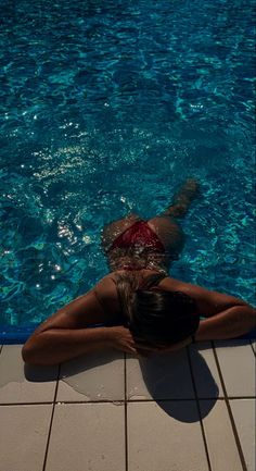 a woman laying on the ground in front of a swimming pool with her back to the camera