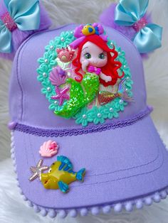 a purple hat with a little mermaid on it