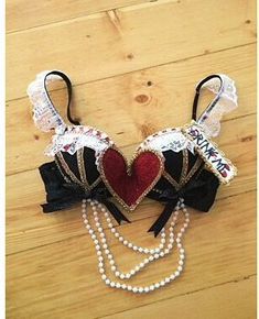 a pair of heart shaped hair clips with pearls and laces on the ends, attached to a wooden floor