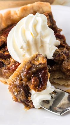 a piece of pecan pie with whipped cream on top and a fork in the foreground