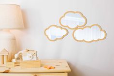 three wooden clouds are hanging on the wall above a table with a camera and toy