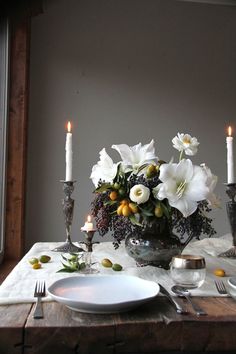 the table is set with white flowers and candles for an elegant centerpiece in this dining room