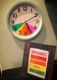 a clock that is on the side of a wall next to a sign reading home work play time dinner bath book bed