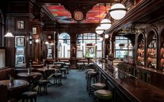 a bar with lots of tables and stools in front of the clock on the wall