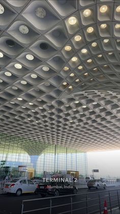 cars are parked in front of the terminal 2 building with circular lights on it's ceiling