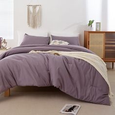 a bed with purple sheets and pillows in a room