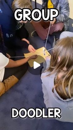 group of young children sitting on the floor playing with cardboard boxes and stringing together