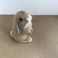 a stuffed rabbit sitting on top of a brown table next to a white wall and floor