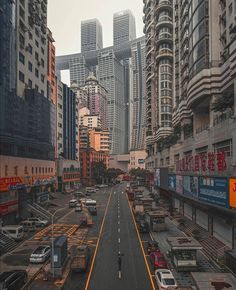 an empty city street with tall buildings in the back ground and cars parked on the side