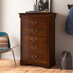 a wooden chest of drawers next to a blue chair