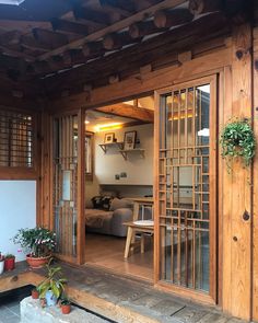 the inside of a house with wooden walls and doors, potted plants on the porch