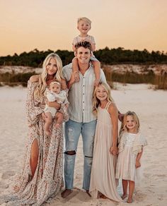 a family poses for a photo on the beach at sunset with their two children and one adult