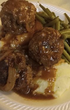 meatballs, mashed potatoes and green beans on a paper plate with gravy