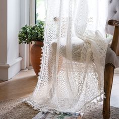 a white crocheted lace curtain hanging from a chair in front of a window