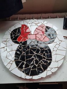 a mickey mouse mosaic on a white plate with red and black pieces in the middle