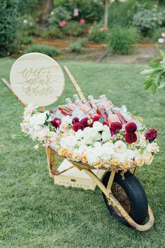 a wheelbarrow filled with wine bottles and flowers