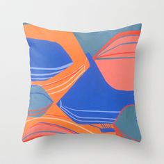 an orange, blue and pink pillow on a white wall with a black frame in the middle