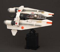 a toy model of a star wars fighter jet on a black base with red and white accents