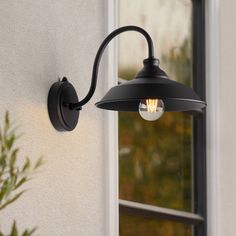 an outdoor light on the side of a house next to a potted plant and window