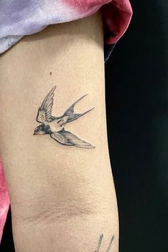 a small bird tattoo on the right arm