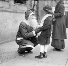 an old black and white photo of two men dressed as santa clausens on the street