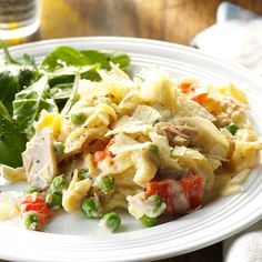 a white plate topped with pasta and veggies on top of a wooden table