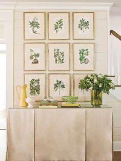 a room with pictures on the wall and flowers in vases next to a table