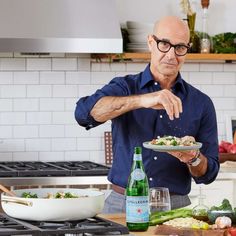 a man standing in a kitchen sprinkling something on a plate