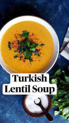 a white bowl filled with soup next to a spoon and some parsley on the side