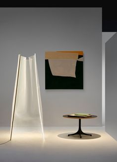 a table with a book on it next to a tall white sculpture in a room