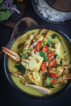 a bowl filled with crab and vegetables next to rice