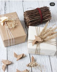 three wrapped presents sitting on top of a white wooden table next to twine sprigs