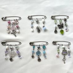 Y2K safety pin charms Handmade with glass, shell, and metal beads. Each pin measures approximately 1 3/4 inch in width. <3 Beaded Safety Pins, Safety Pin Bag Charm, Safety Pin Beads, Y2k Crafts, Safety Pin Keychain, Y2k Charms, Safety Pin Charms, Bead Pins, Saftey Pin