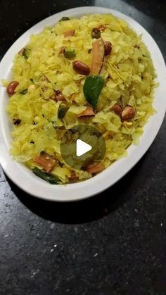 a white bowl filled with rice and nuts on top of a black table next to a knife